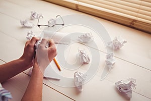 Hands crumpling paper on wooden desk