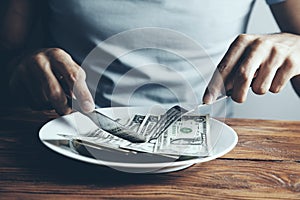 Hands cut money on plate reduce funds concept