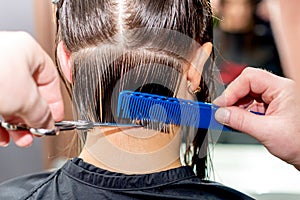 Hands cuts hair of woman