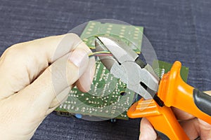 Hands cuts wires with wire cutters, chip in the background