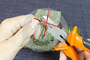 Hands cuts wires with wire cutters, chip in the background