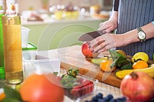 Hands cutting an apple on chopping board. Young woman preparing a fruit salad in her kitchen