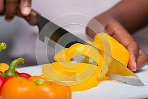 Hands cutting bell peppers with knife, food preparation