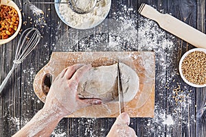 Hands cutting dough. Preparation recipe bread, pizza or pie making ingridients, food flat lay on kitchen table background