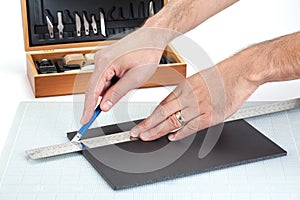 Hands cutting a foam board with sharp knife
