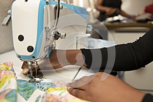 Hands of a dark-haired woman using an industrial sewing machine