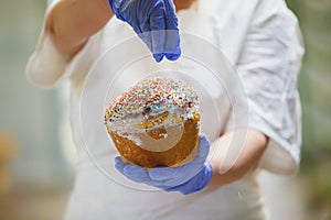 Hands decorate Easter bun.