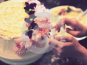 Hands decorating a cake with flowers