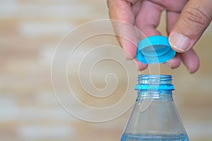 hands delicately twist open the cap of a refreshing bottle of water, ready to quench a thirst