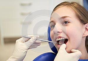 Hands with dental mirror checking girl teeth