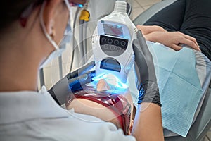 Hands of dentist keeping equipment radiating ultraviolet