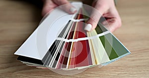 Hands of designer opening fan with color swatches in studio closeup 4k movie slow motion