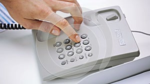 Hands dialing number on desk set phone at office