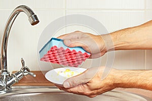 Hands with dirty plate over the sink in kitchen