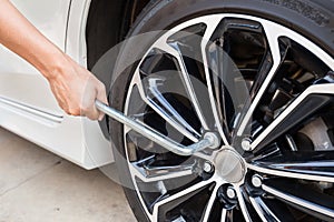 Hands disassembling a modern car wheel (steel rim) with a lug wrench