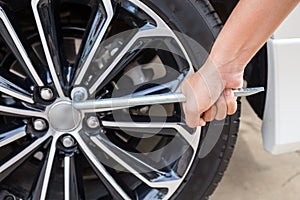 Hands disassembling a modern car wheel (steel rim) with a lug wrench