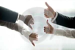 Hands of diverse business people showing thumbs up and down