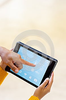 Hands of diverse couple, holding tablet and pointing to smart home interface on screen, copy space
