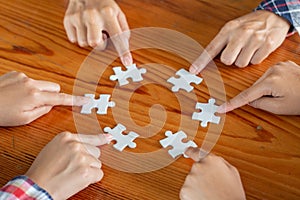 Hands of diverse people assembling jigsaw puzzle, team put pieces together searching for right match, help support in teamwork to
