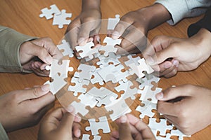 Hands of diverse people assembling jigsaw puzzle, team put pieces together searching for right match, help support in teamwork to