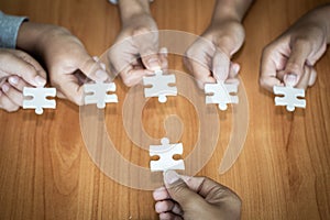 Hands of diverse people assembling jigsaw puzzle, team put pieces together searching for right match, help support in teamwork to