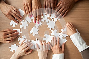 Hands of diverse people assembling jigsaw puzzle together, top v