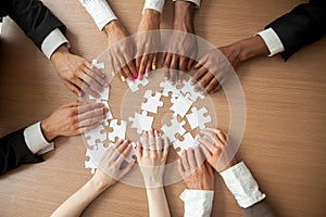 Hands of diverse people connecting puzzle together, top closeup