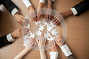 Hands of diverse people connecting puzzle together, top closeup photo