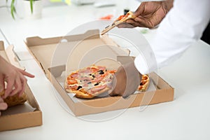 Hands of diverse people taking pizza slices, close up view