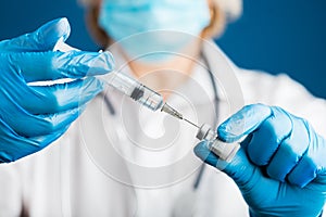 Hands of a doctor in medical gloves draws a liquid vaccine against the corona virus covid 19 into a syringe from a vial preparing