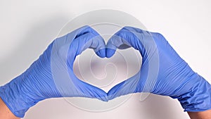 Hands of a doctor or nurse in medical gloves depict a heart on a white background, caring doctor and medicine concept