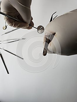 hands of doctor with white latex gloves using dental tools for oral inspection