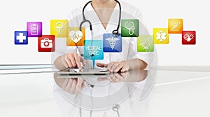 Hands of doctor woman touch digital tablet at office desk with medical symbols icons isolated on white