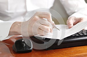 Hands with document on computer keyboard