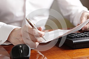 Hands with document and pen on a computer keyboard