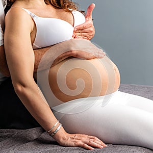 Hands doing abdomen massage on pregnant belly.