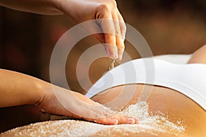 Hands doing salt exfoliation massage on woman
