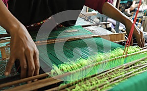Hands doing weaving work using traditional tools