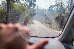 Hands of a driver on steering wheel of a car on the road