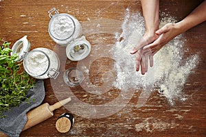 Hands dusting off flour baking scene flour on wooden table