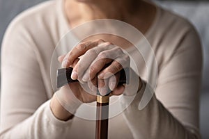 Hands of elder woman holding knob of walking cane