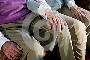 Hands of elderly couple touching on knee