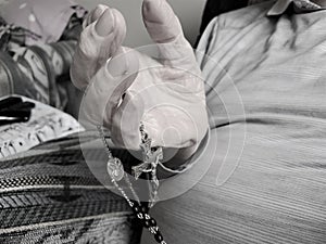 Hands of elderly man holds rosary beads