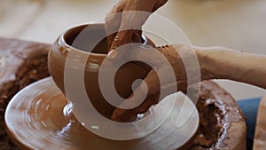 Hands of an elderly potter working with clay on a potter's wheel