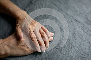 Hands of an elderly seigneur on a gray faded tablecloth. Senior old lady experiencing severe arthritis rheumatics pains photo