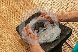 Hands of an elderly woman, grinding dough in the metate for the elaboration of blue tortillas, which is a typical Mexican food photo