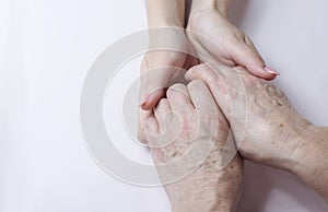 Hands of an elderly woman in the hands of a young woman caring for old age