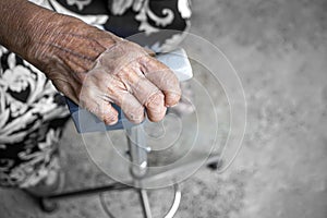 The hands of an elderly woman have curly fingers and wrinkled, holding the old cane sitting alone