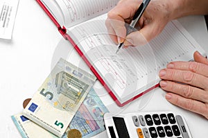 The hands of an elderly woman holding a pen working on a utility bill calculator