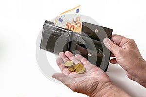 Hands of an elderly woman with a money purse and few euro coins and banknotes, cash check in the economic crisis affected by